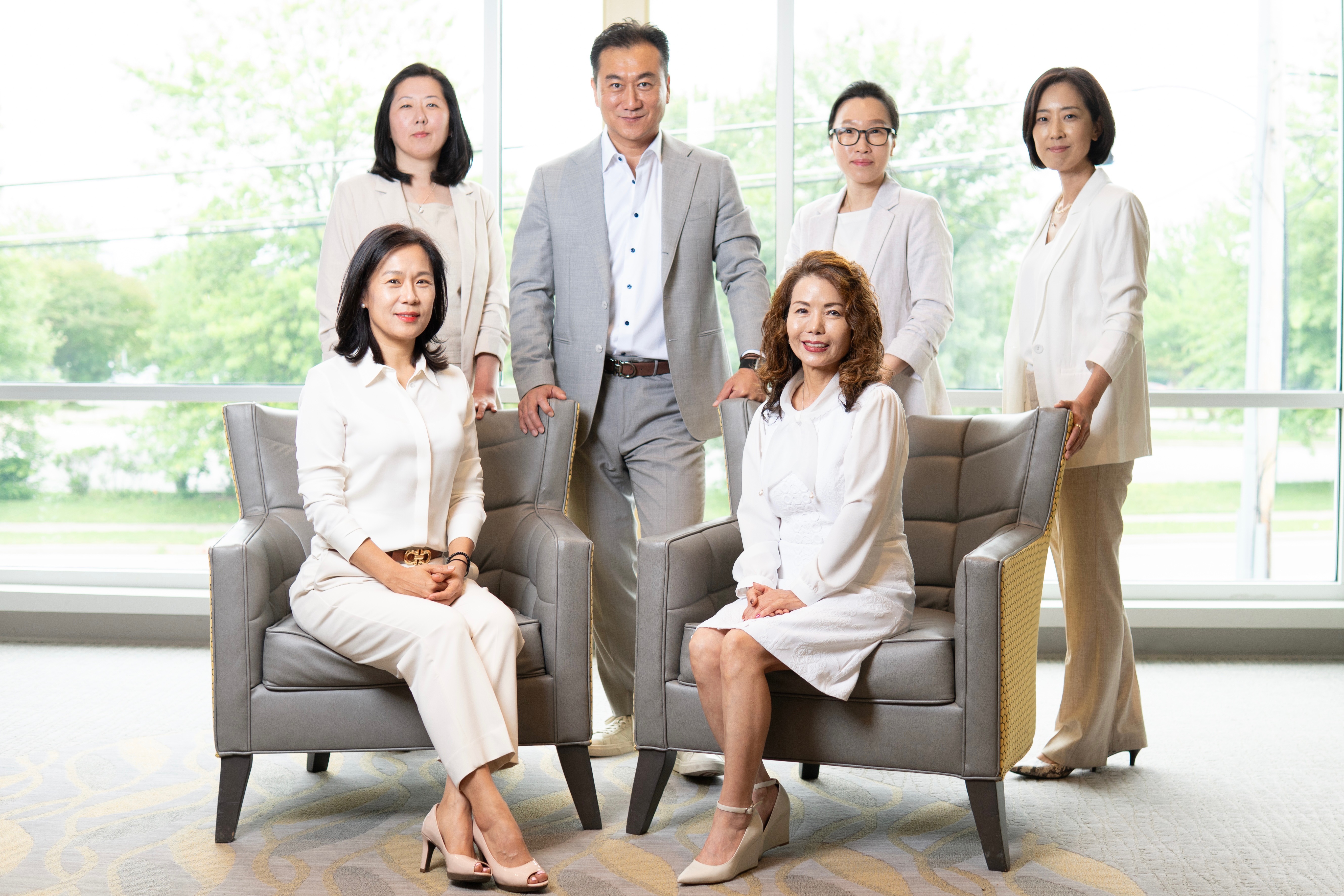 The Keith Jang Group smiling while wearing a blue or black jacket. 